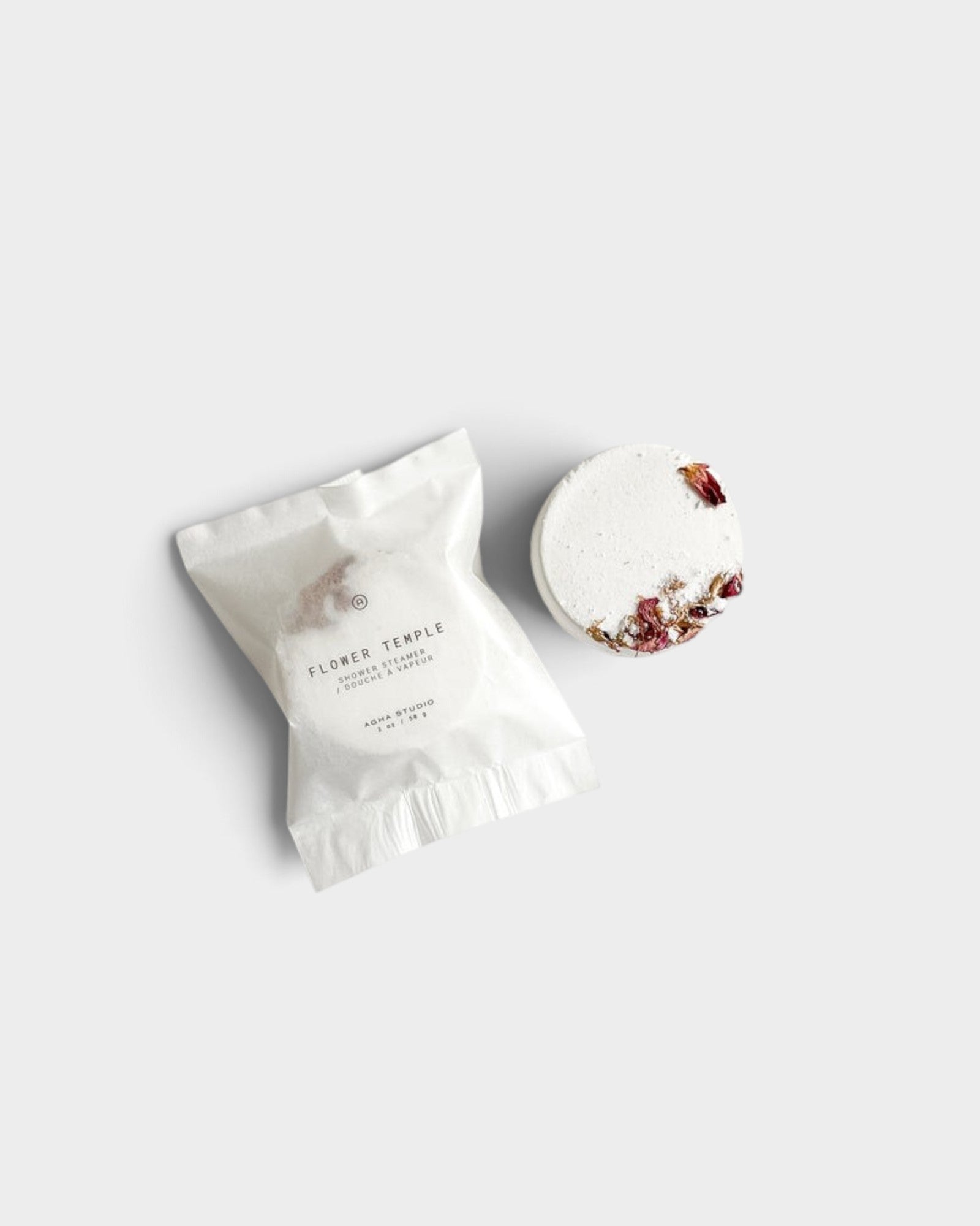 JONES + CO Flower Temple shower steamer with dried floral petals in white paper packaging on a neutral background.