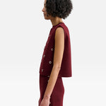 Model wearing JONES + CO garnet red baby alpaca Vega Vest with metallic eyelets in a boxy sleeveless silhouette