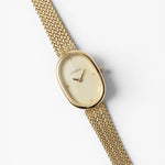 JONES + CO Jane Tethered watch with a gold oval case, champagne mother-of-pearl dial, and woven mesh bracelet.