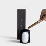 JONES + CO gold USB arc lighter igniting a black candle with a minimalist gift box in the background.