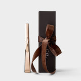 JONES + CO gold USB arc lighter standing next to a black gift box with a brown velvet ribbon.