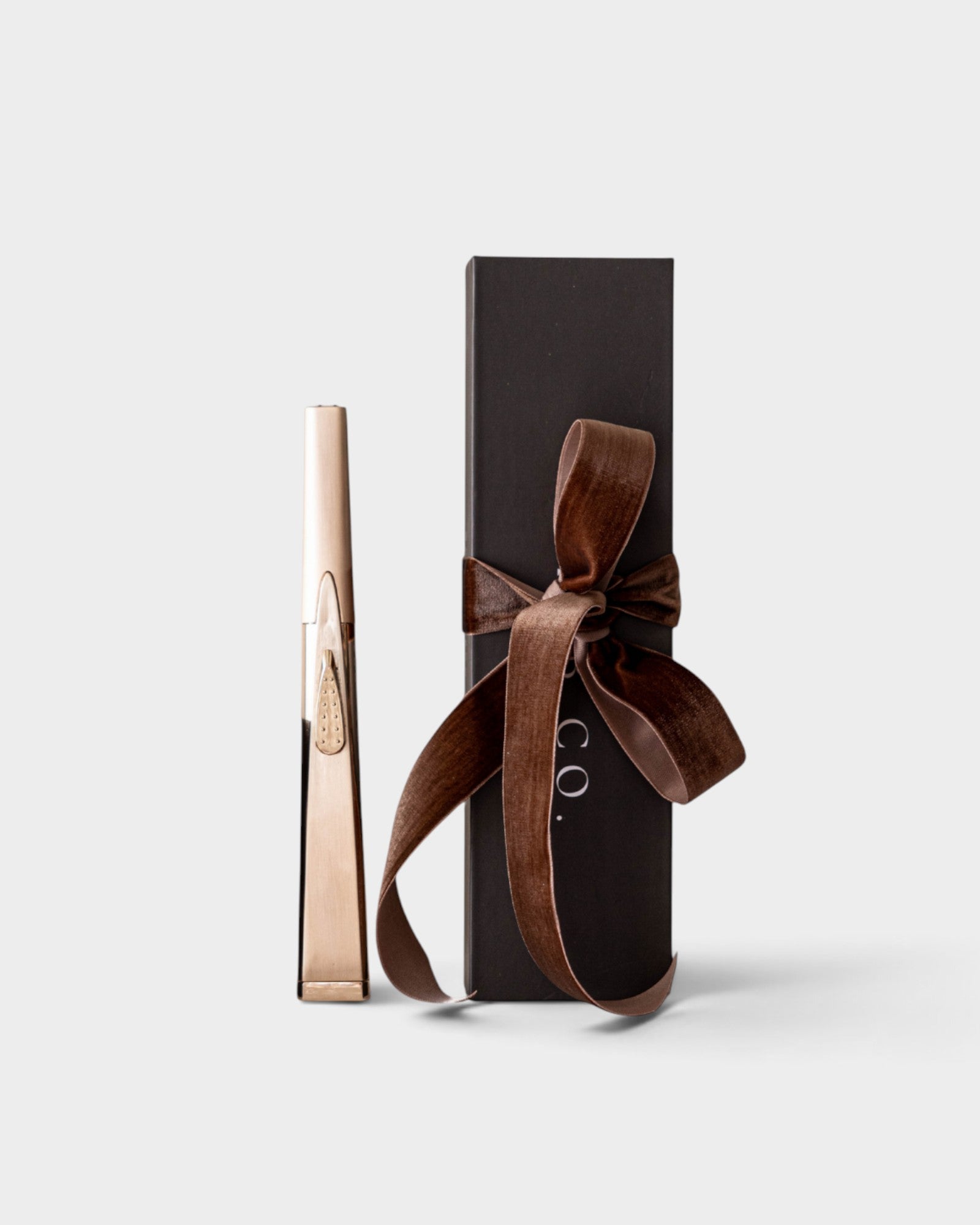 JONES + CO gold USB arc lighter standing next to a black gift box with a brown velvet ribbon.