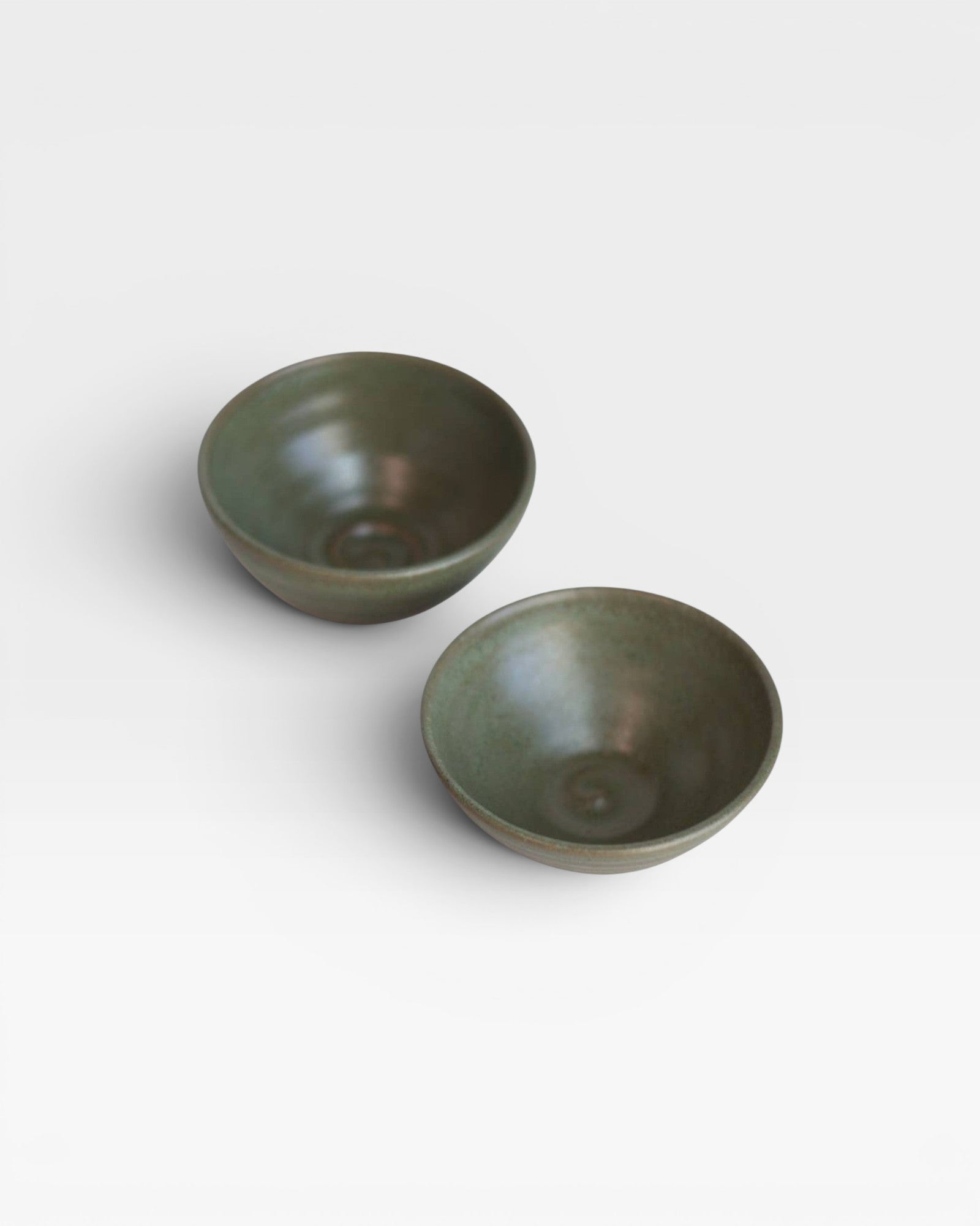 Two JONES + CO handcrafted green ceramic little bowls for snacks, trinkets, or home decor on a white background.