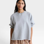 JONES + CO Rachel Comey grey crewneck sweatshirt with drop shoulders, cropped sleeves, and a raw edge hemline.