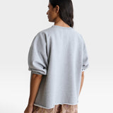 JONES + CO grey crewneck sweatshirt with drop shoulders and raw edge hem worn by a model from the back