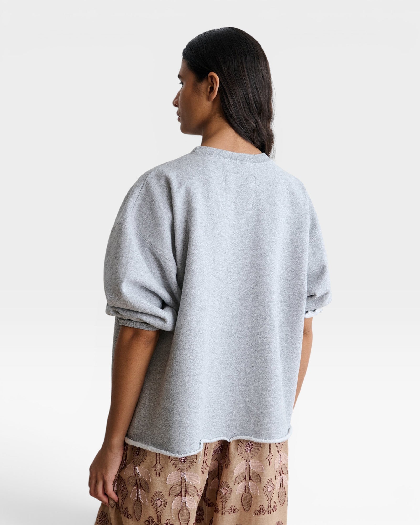 JONES + CO grey crewneck sweatshirt with drop shoulders and raw edge hem worn by a model from the back