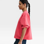 JONES + CO Fond crewneck sweatshirt in guava pink with drop shoulders, cropped sleeves, and raw edge hemline.