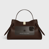 JONES + CO Gyoza pouch in fennel brown suede with a top handle, gold hardware, and size reference to an iPhone 16.