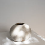 JONES + CO handthrown ceramic vase with a speckled off-white glaze and round sculptural shape on a white surface.