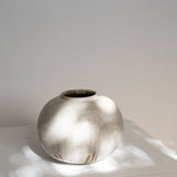 JONES + CO handthrown ceramic vase with a speckled off-white glaze and round sculptural shape on a white surface.