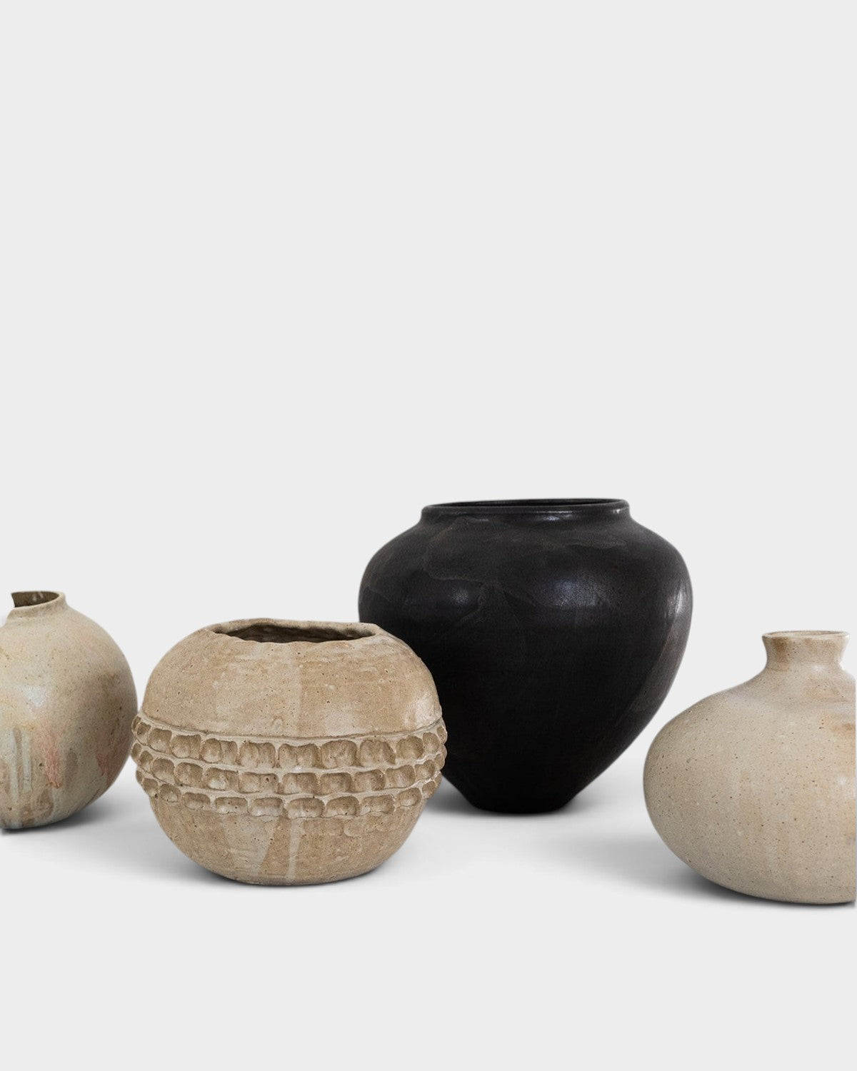 JONES + CO collection of four unique handthrown ceramic vases in neutral beige and matte black tones.
