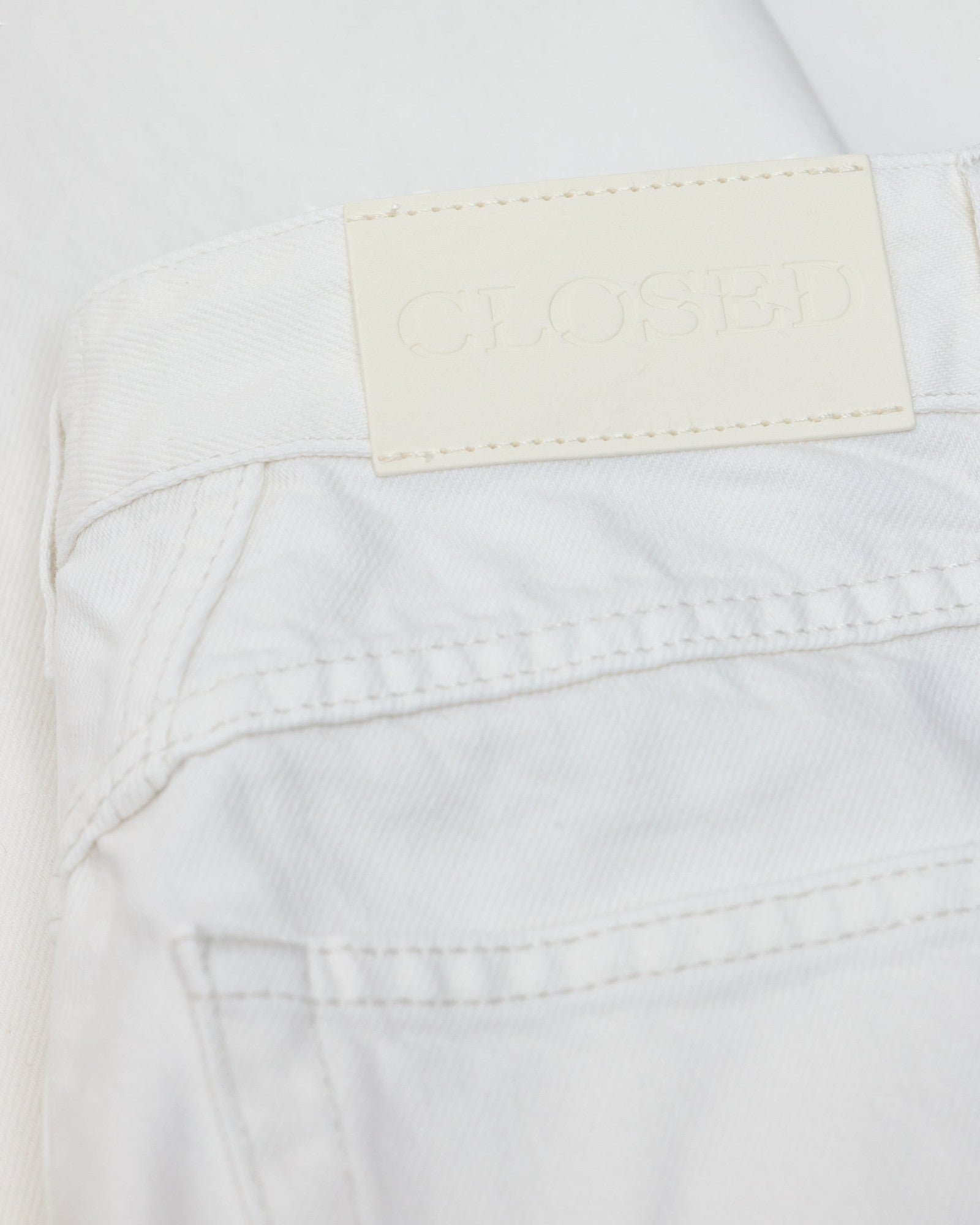 JONES + CO Jayla ivory white rigid denim jeans featuring a branded leather back patch and detailed stitching