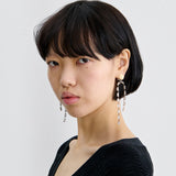 Model wearing JONES + CO ivory acrylic and brass draped baguette drop earrings against a plain white background.