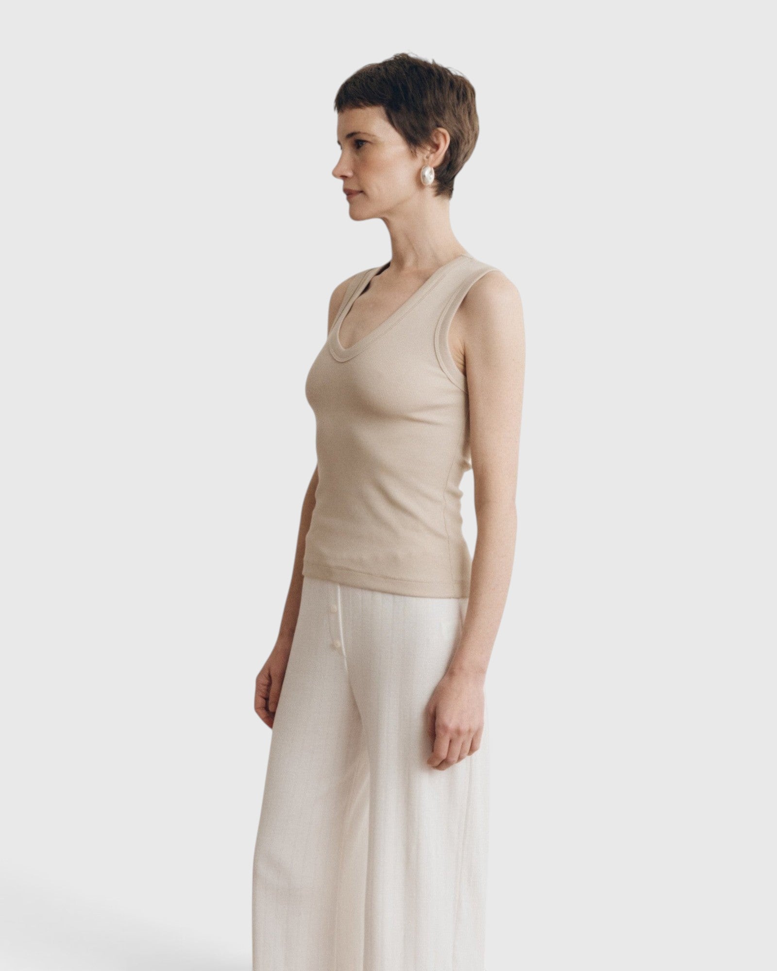 JONES + CO Kana Tank in dune beige featuring a deep scoop neckline and finely ribbed knit fabric on a model