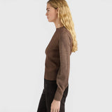 JONES + CO Loa ribbed lurex turtleneck top in caramello brown with long amphora sleeves on a model, side view.