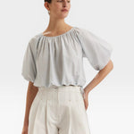 JONES + CO Lotus cropped blouse in light blue with French knot embroidery, short sleeves, and drawstring waist.
