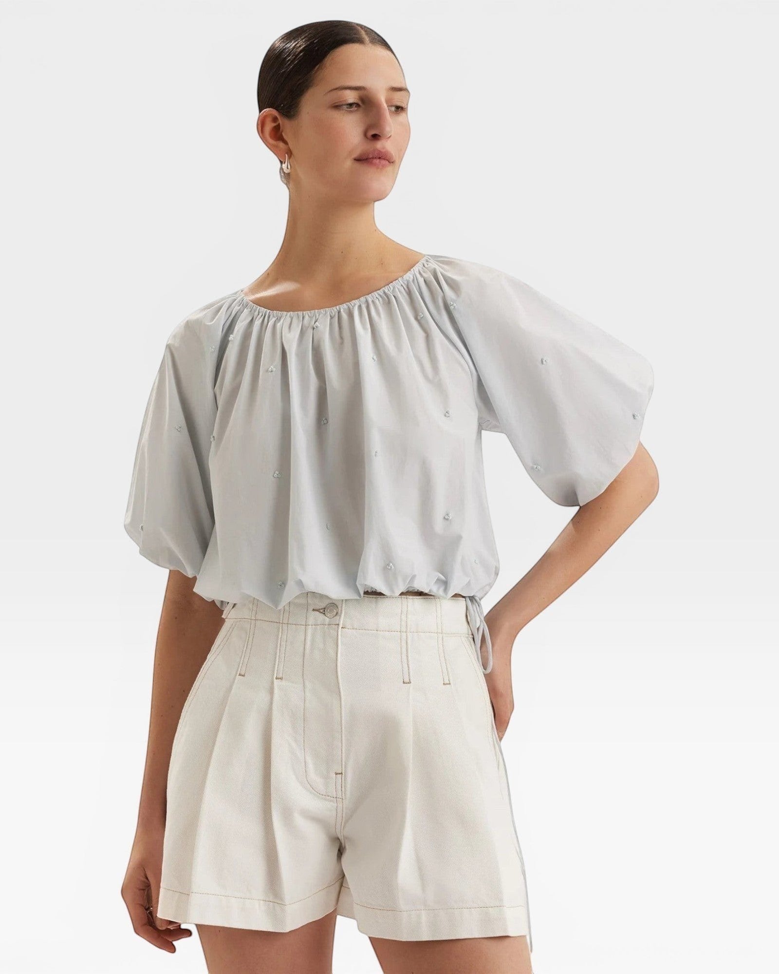 JONES + CO Lotus cropped blouse in light blue with French knot embroidery, short sleeves, and drawstring waist.