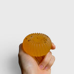 JONES + CO lülala basil and mandarin soap bar with calendula petals held in a hand against a white background.