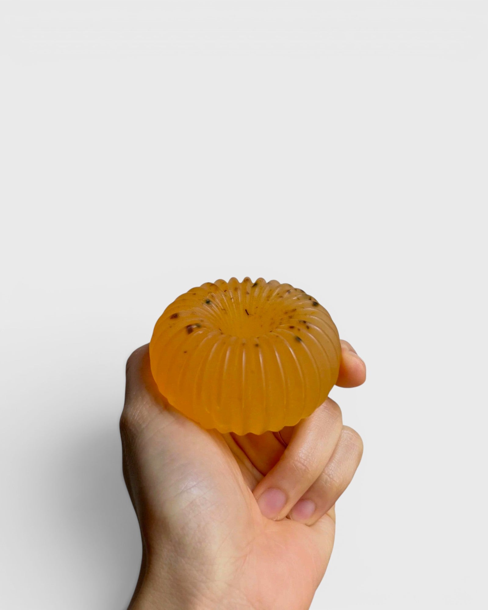 JONES + CO lülala basil and mandarin soap bar with calendula petals held in a hand against a white background.