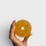 JONES + CO lülala basil and mandarin soap bar with calendula petals held in a hand against a white background.