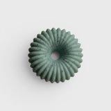 JONES + CO lülala bergamot and pink pepper soap bar in a pale green, fluted ring shape with speckled botanicals.