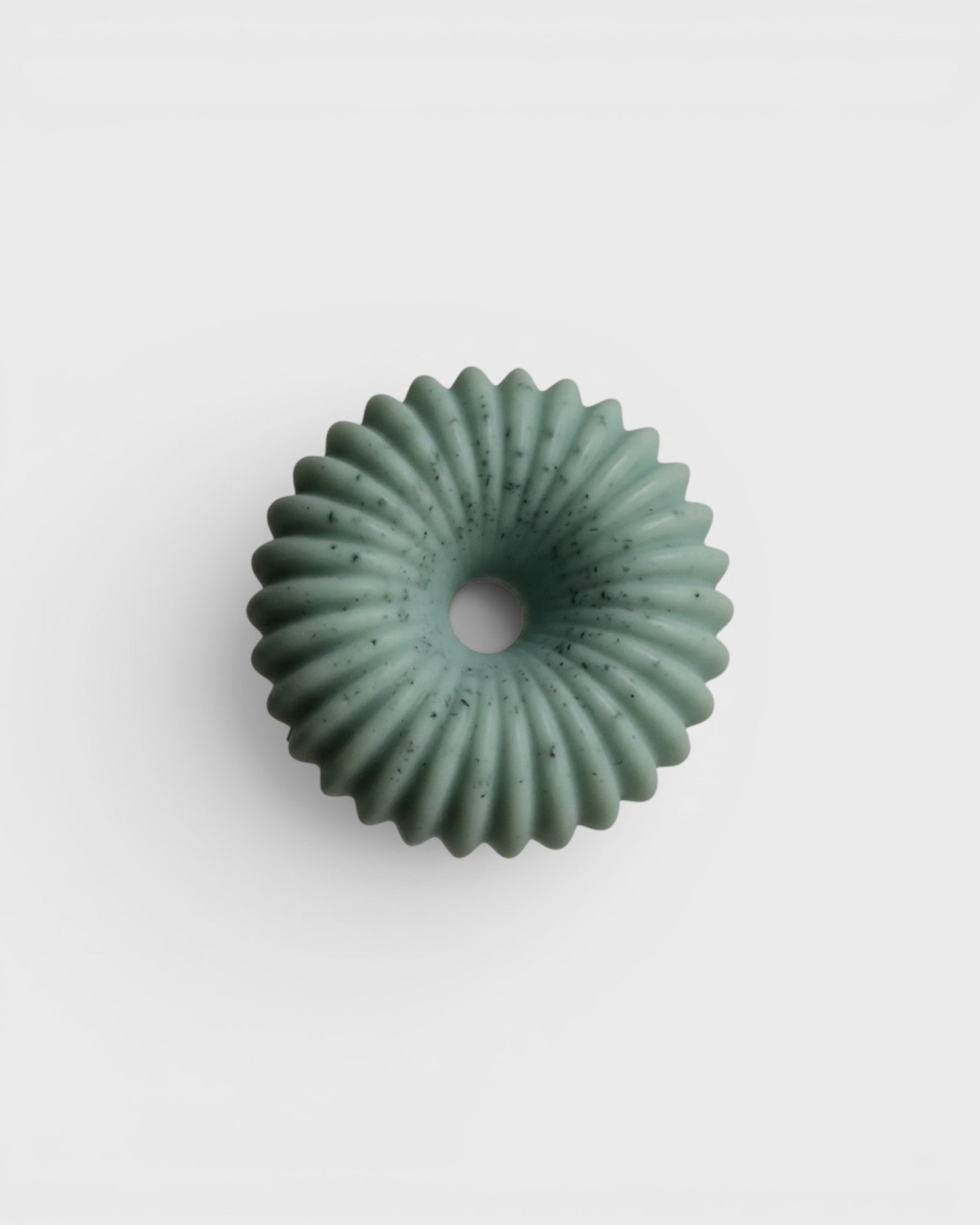 JONES + CO lülala bergamot and pink pepper soap bar in a pale green, fluted ring shape with speckled botanicals.
