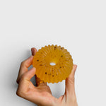 JONES + CO lülala soap bar in translucent orange with calendula petals, held in a hand against a white background.