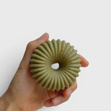 JONES + CO lülala May Chang and Coriander soap bar with a unique ribbed geometric shape held in a hand.