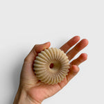JONES + CO lülala vetiver and makrut lime soap bar with a unique fluted, donut-like shape held in a hand.
