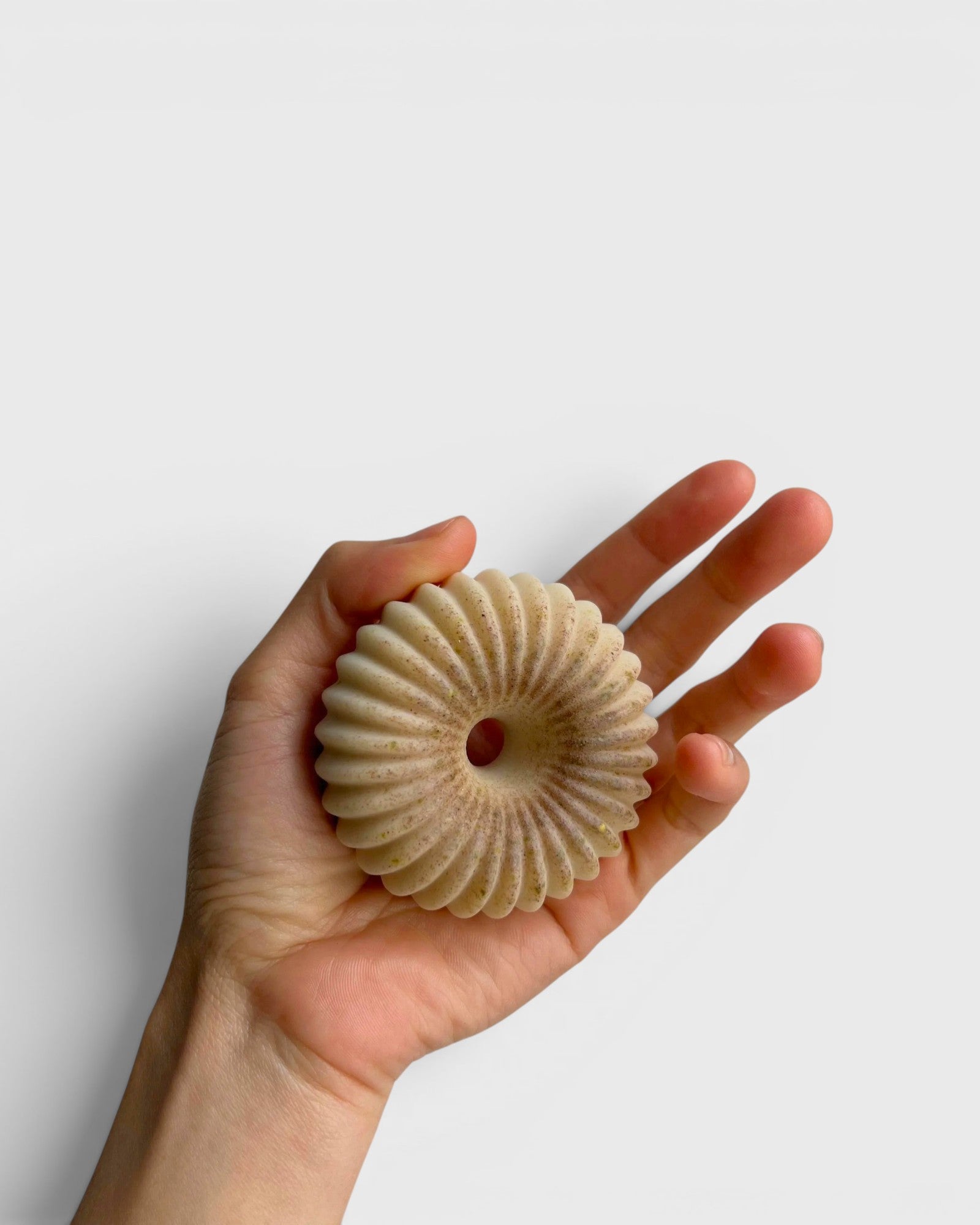 JONES + CO lülala vetiver and makrut lime soap bar with a unique fluted, donut-like shape held in a hand.