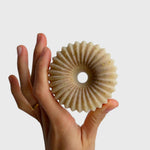 JONES + CO lülala vetiver and makrut lime soap bar with a fluted, circular design held in a hand.