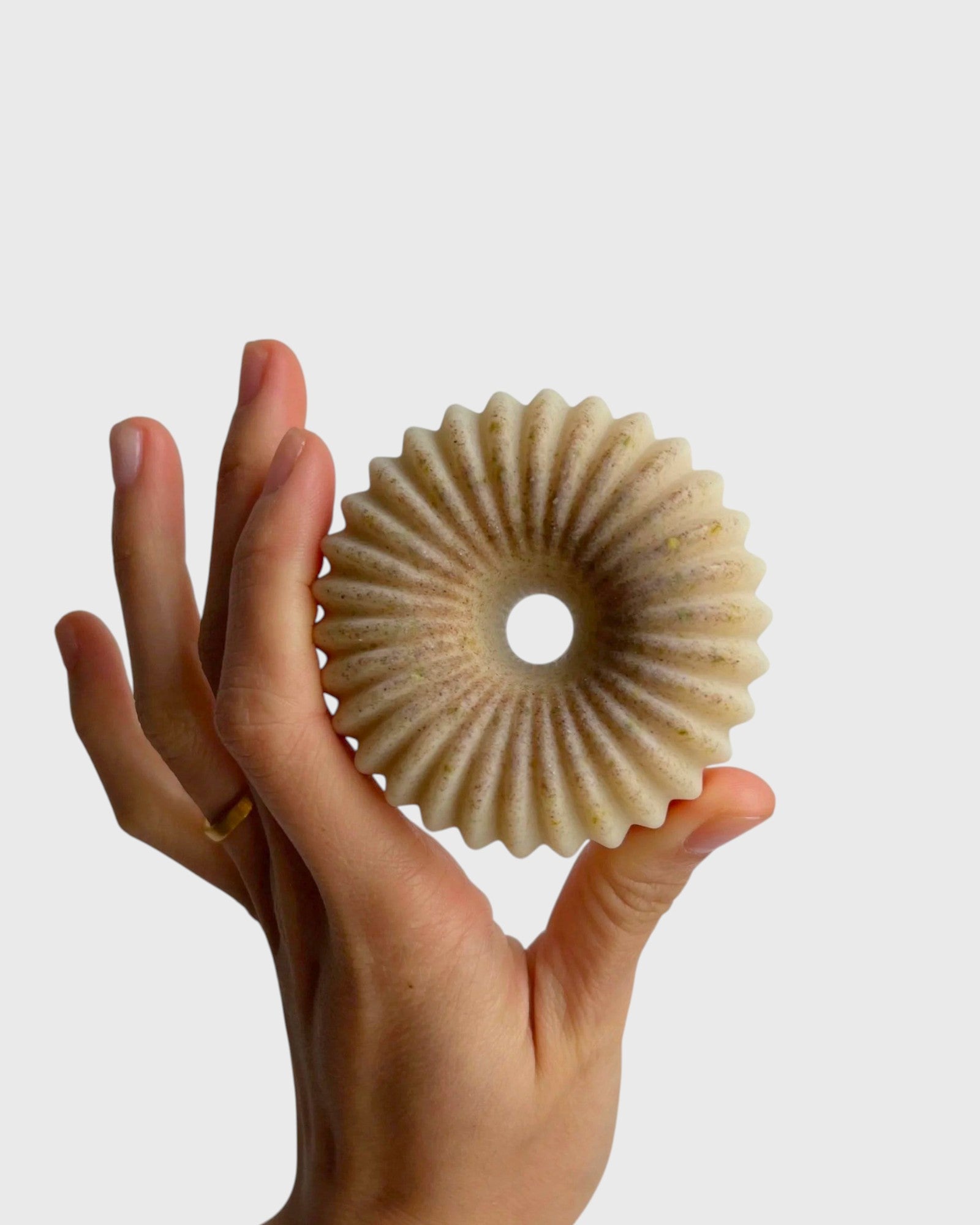 JONES + CO lülala vetiver and makrut lime soap bar with a fluted, circular design held in a hand.