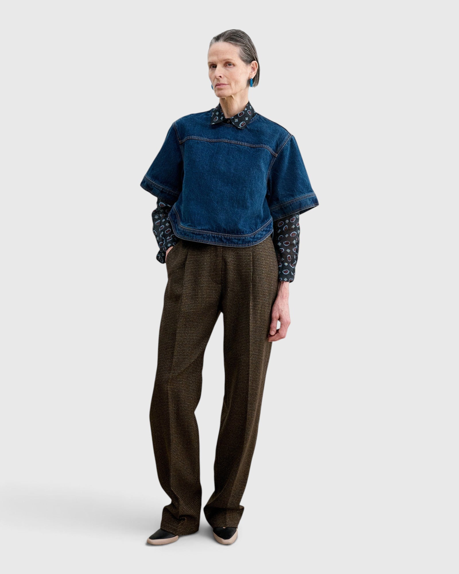 JONES + CO Fort Top in muddy indigo denim worn over a patterned shirt and brown trousers by a model