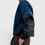 JONES + CO Fort Top in muddy indigo denim with a boxy silhouette, layered over a patterned long-sleeve shirt.