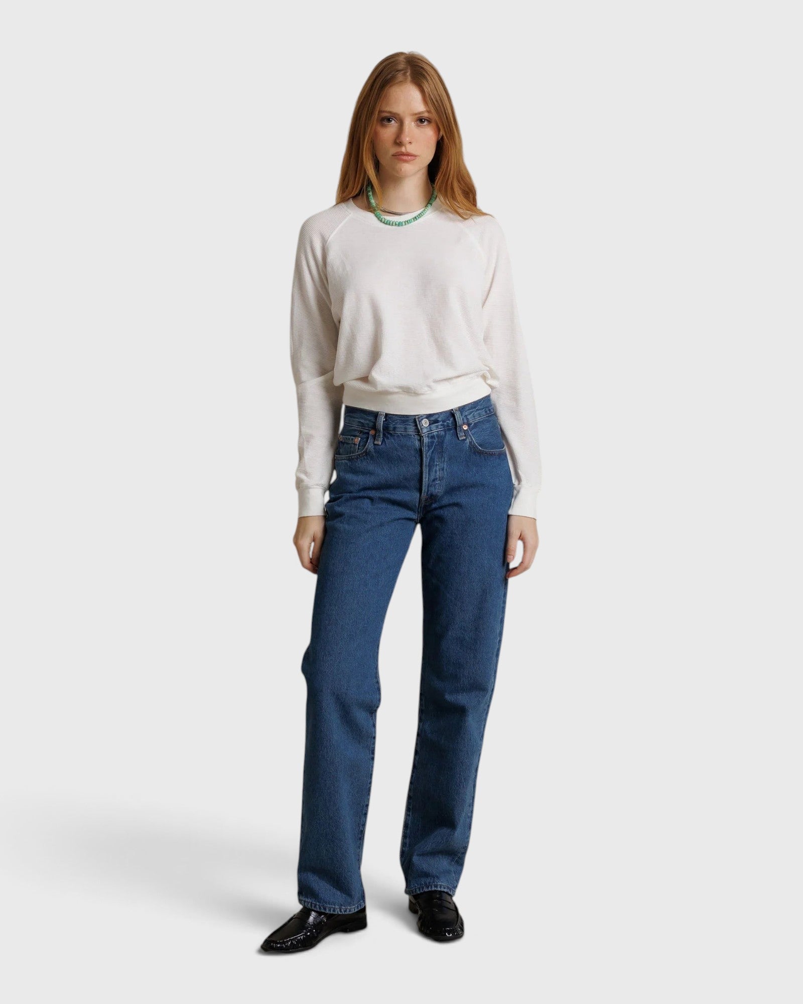 Model wearing a JONES + CO natural textured jersey crew neck sweater with long sleeves and blue denim jeans