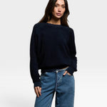 Model wearing a JONES + CO navy blue Ziggy sweatshirt with long sleeves and a crew neckline paired with blue jeans