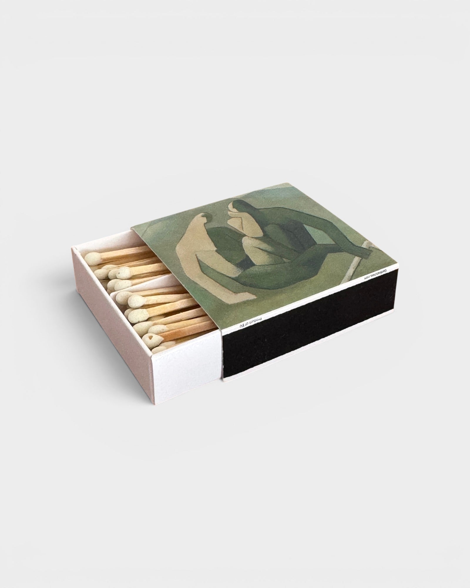 JONES + CO Nue matchbox featuring artistic green and beige abstract figures on a wooden surface