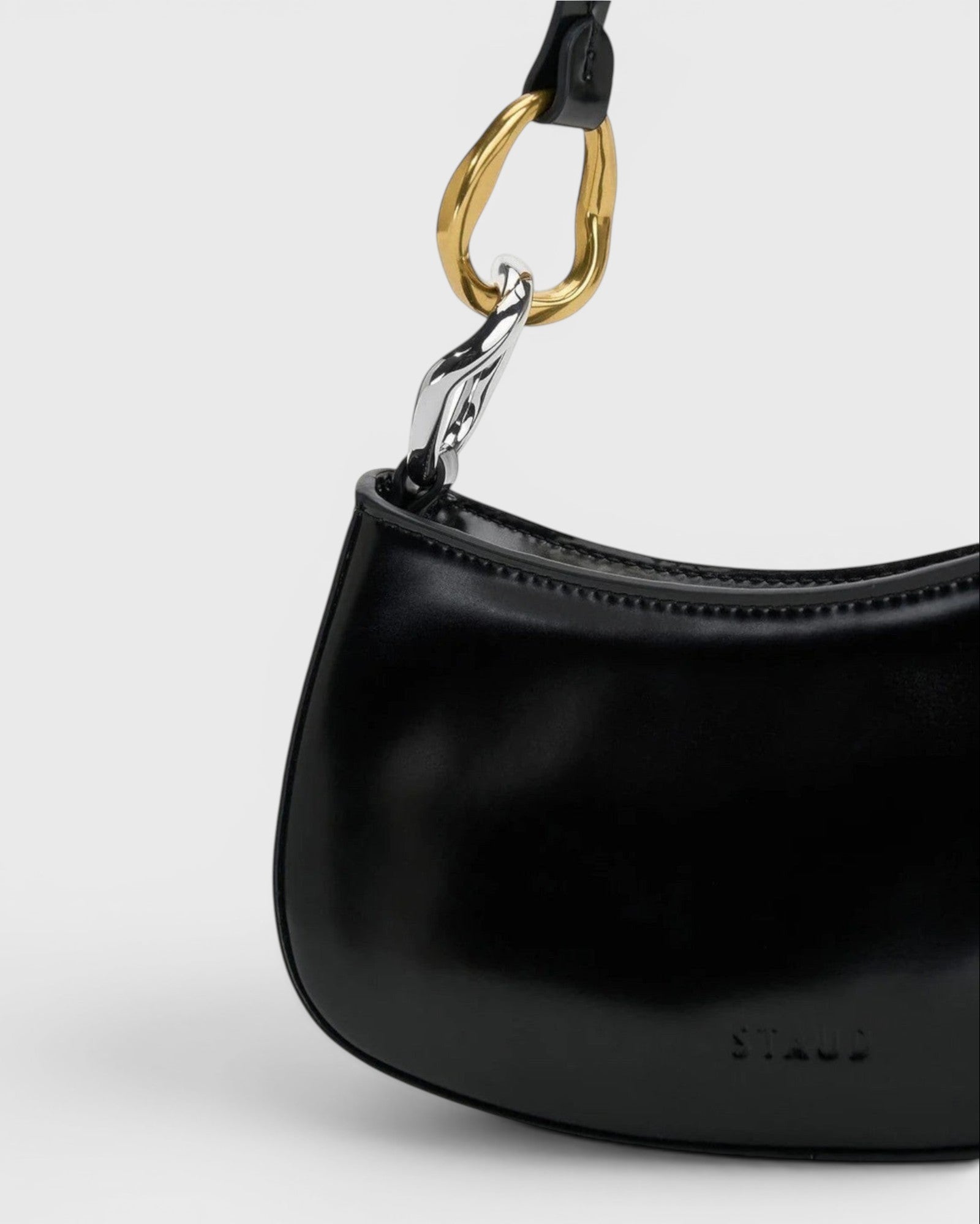 JONES + CO Ollie Bag in black polished leather with a unique two-tone gold and silver hardware strap detail.