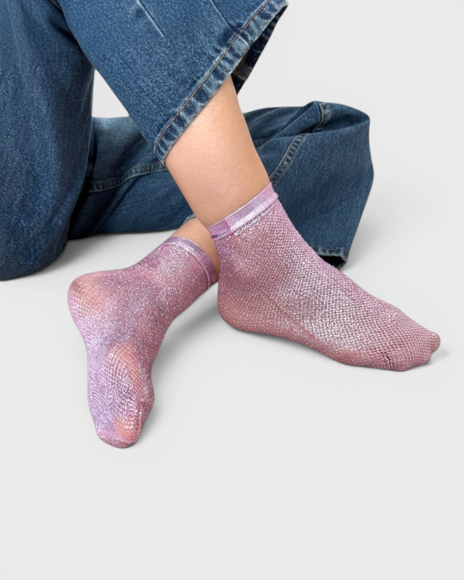 JONES + CO pink laminated net socks with a ribbed texture worn on a model in blue jeans.
