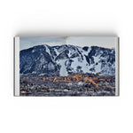 JONES + CO Private Aspen book open to a panoramic photograph of the snowy Aspen mountain landscape at twilight.