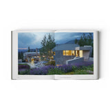 JONES + CO Private Aspen book open to a photograph of a modern mountain home with stone walls and lavender gardens.