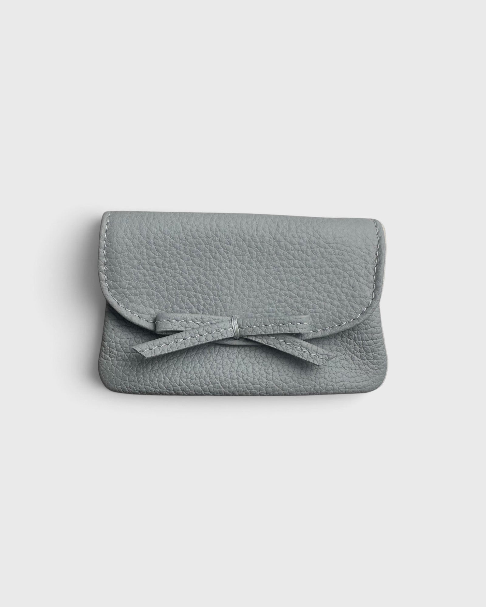 JONES + CO Provence Blue leather petite case with a front flap, knotted bow detail, and hidden magnetic closure.