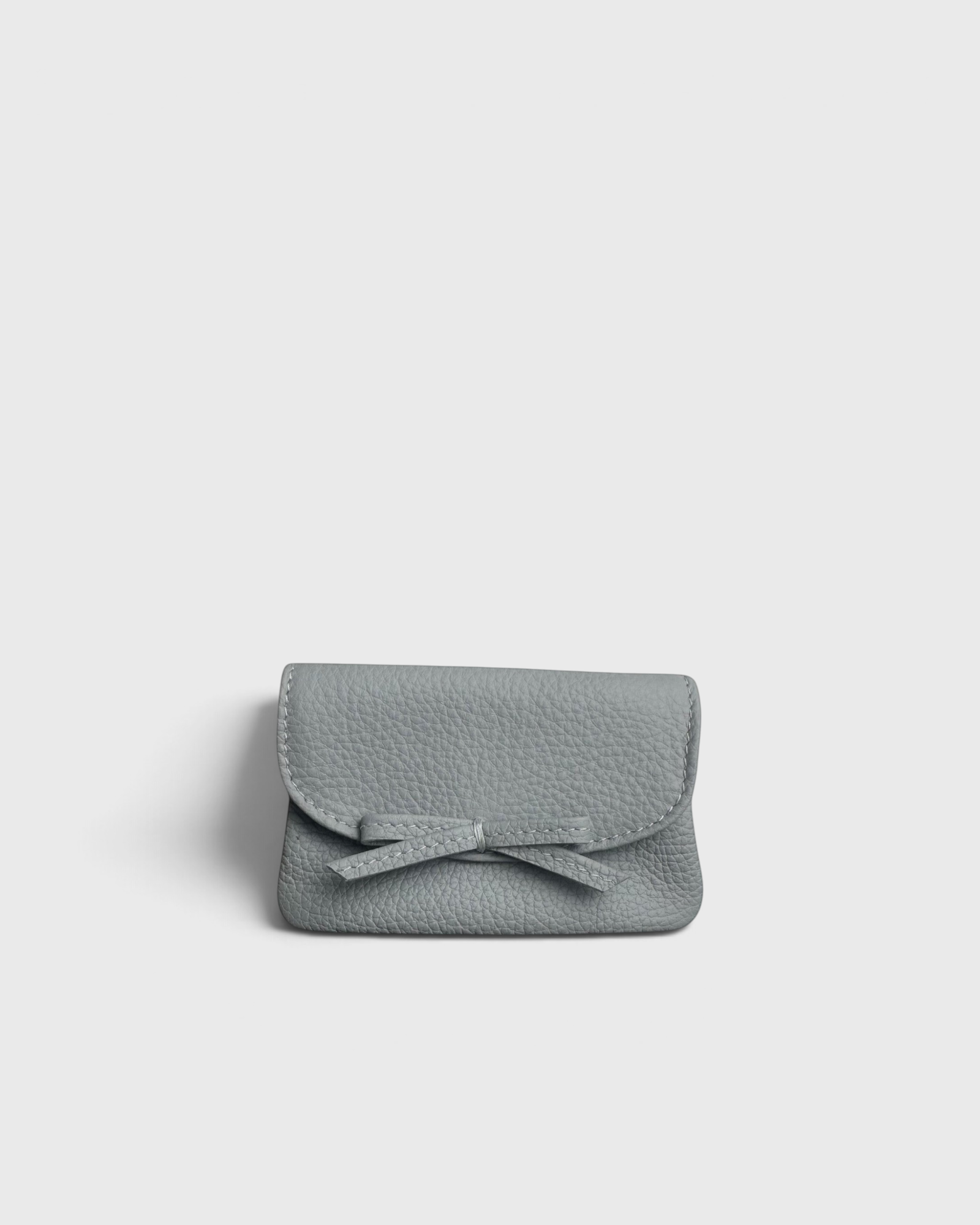 JONES + CO Provence Blue leather petite case with a front flap, knotted bow detail, and hidden magnetic closure.