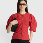 JONES + CO red crew-neck top with button front and short puff sleeves worn by a woman with sunglasses