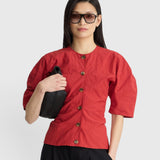 JONES + CO red crew-neck top with button front and short puff sleeves worn by a woman with sunglasses