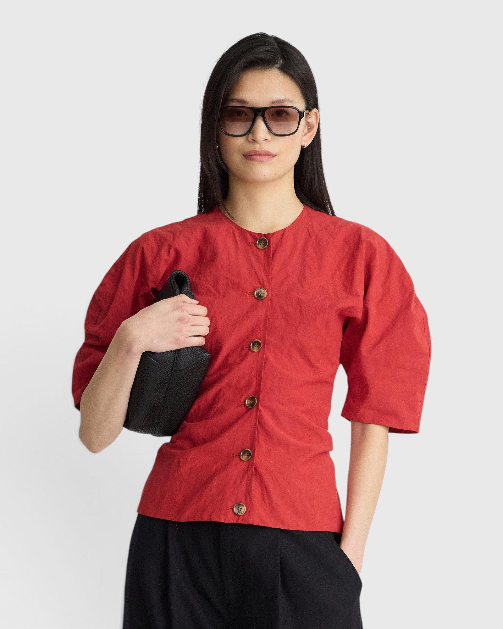 JONES + CO red crew-neck top with button front and short puff sleeves worn by a woman with sunglasses