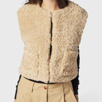 JONES + CO reversible short vest in oatmeal beige faux fur, featuring a collarless design and soft wool blend texture.