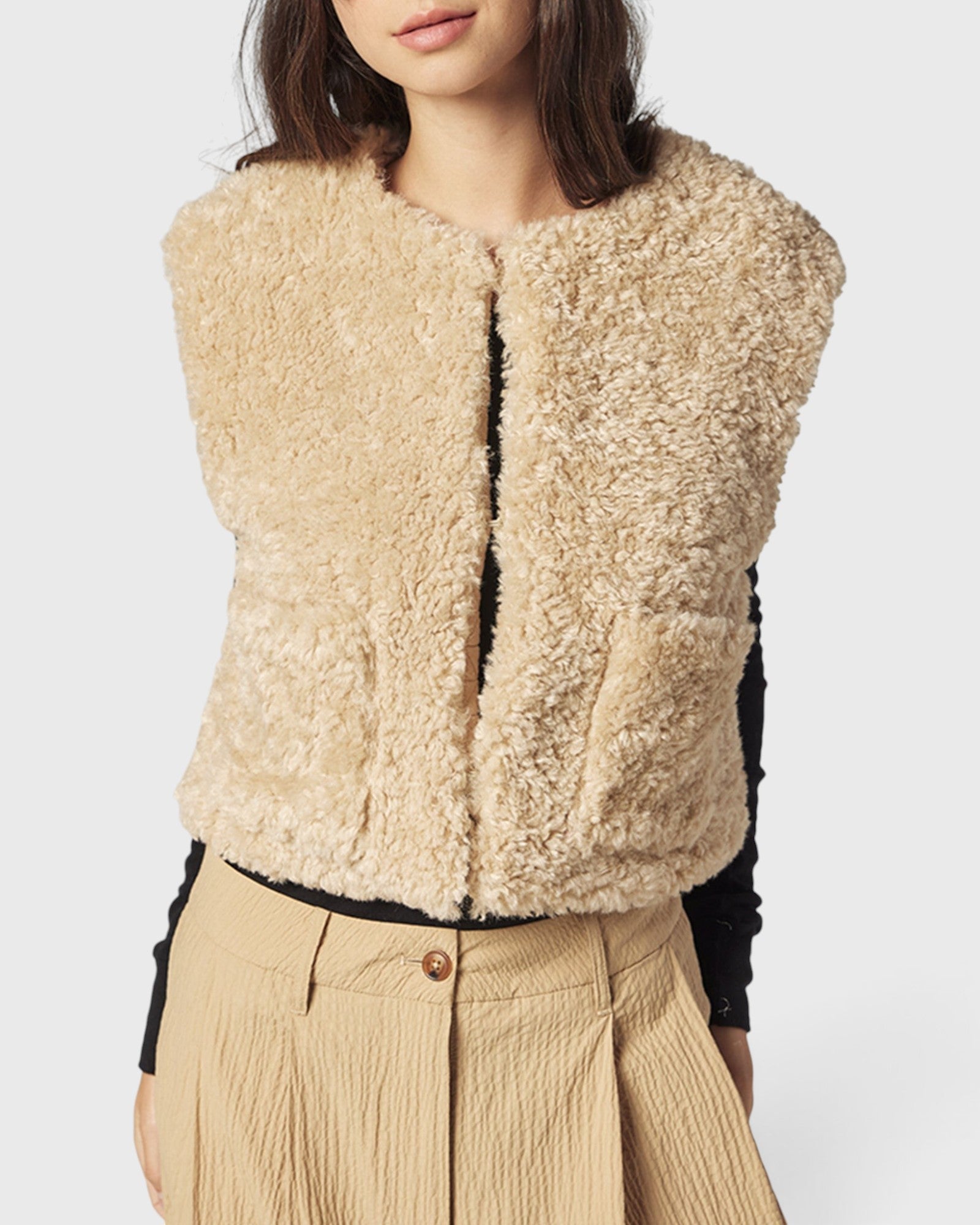 JONES + CO reversible short vest in oatmeal beige faux fur, featuring a collarless design and soft wool blend texture.