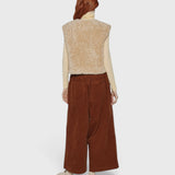JONES + CO reversible oatmeal beige faux fur short vest worn over a cream turtleneck and brown corduroy trousers