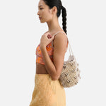 Model wearing a JONES + CO silver leather macrame mini web bag with bamboo beads over her shoulder